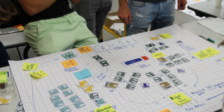 Photographie représentant un plan sur grand format papier pendant un atelier, avec des participants autour du plan 