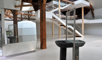 Photographie représentant un leu d’exposition dans lequel on aperçoit un igloo géométrique blanc et des dispositifs de tests de matériaux