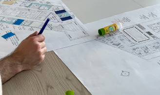 Photographie représentant des plans sur lesquels des participants à un atelier sont en train d'annoter et de dessiner